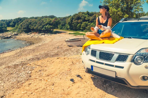 Deniz yaz plajında mutlu bir kadın araba kaputu tatilinde oturuyor.
