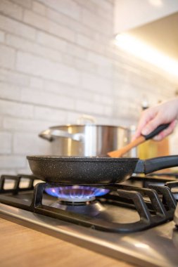 frying pan on cooking top blue flame close up