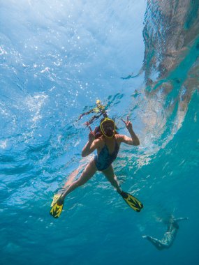 Şnorkel maskesi ve yüzgeçleriyle suyun altında yüzen güzel bir kadın.