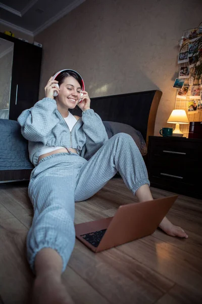 在家里用笔记本电脑工作的女自由职业者坐在卧室的地板上 — 图库照片