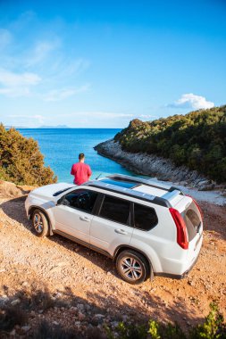 Deniz kıyısı gezisinde SUV arabalı bir adam.