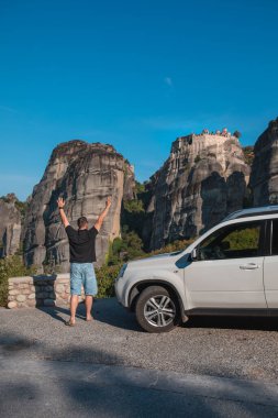 Yunanistan araba yolculuğu konsepti. Cipin yanında duran bir adam meteora manastırına bakıyor.