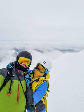Çift kayakçı ve snowboardcu dağın tepesindeki fotokopi alanında selfie çekiyorlar.