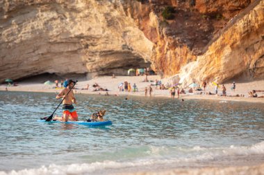 Lefkada, Yunanistan - 7 Eylül 2021: Köpek deniz tatili ile kürek çeken adam