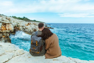 Uçurumda oturup denize bakan çift. büyük dalgalar.