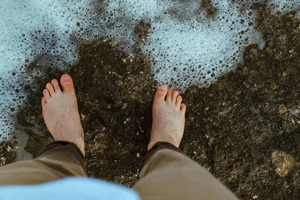 overhead view man barefoot walking by sea rocky beach. copy space