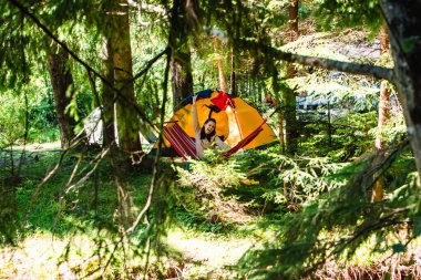 Kadınlar yaz mevsiminde hamakta ormanın arka planındaki çadırda uzanıyorlar.