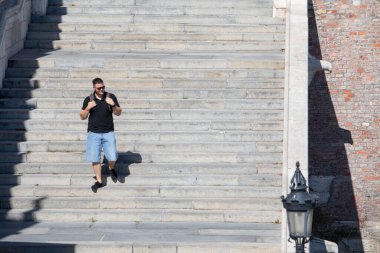 İnsanlar güneşli bir günde taştan merdivenlerde yürüyorlar.