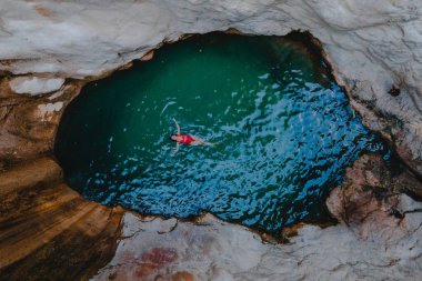 overhead view of dimosari waterfall lake with happy woman floating on the back Lefkada island Greece