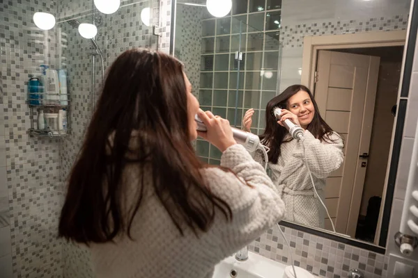 beautiful woman with hair dryer in front of mirror bathroom