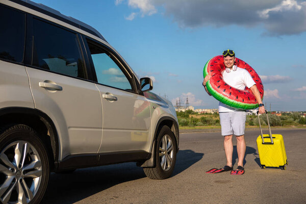 happy man in flippers inflatable ring with bag going to car sea vacation concept