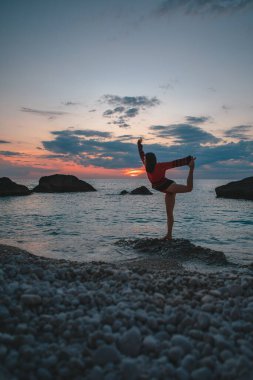 Seksi kadın deniz fenerinin üstündeki günbatımının keyfini çıkarıyor.