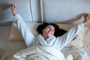 morning in bed woman awaking laying down in bed with white sheets bright room