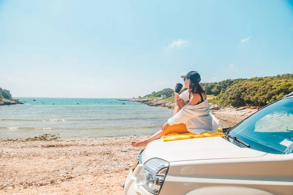 女人坐在车篷边喝咖啡 欣赏夏日的海景 — 图库照片