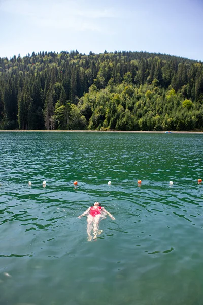 woman floating on back in red swimsuit mountain lake