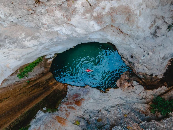 overhead view of dimosari waterfall lake with happy woman floating on the back Lefkada island Greece