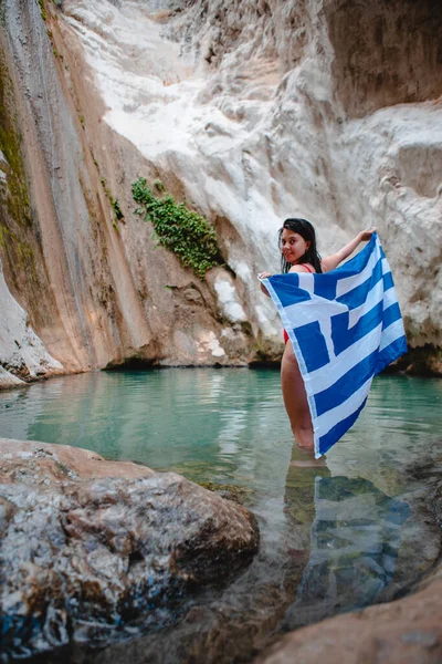 莱夫卡达岛著名地标上身穿红色泳衣 头戴希腊国旗的女子迪莫萨里瀑布 — 图库照片
