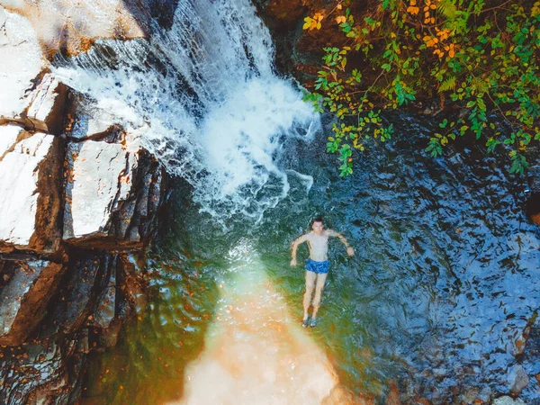 overhead view of man swimming in autumn waterfall copy space