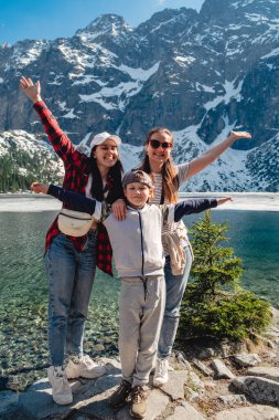 Mother with son and aunt are standing on the shore of a lake. Morskie Oko, Tatras mountains. Poland