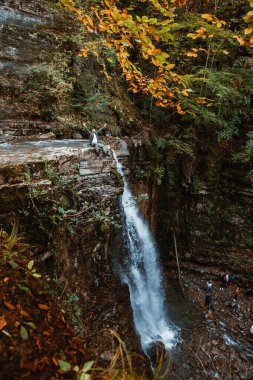 Sonbahar ormanındaki şelalenin tepesindeki adam fotokopi uzayı.