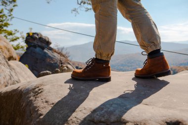 hiking concept men legs in boots on the rock autumn season