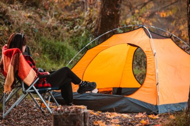 woman sitting on the chair near tent autumn camping season