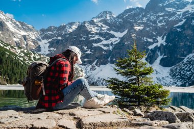 A woman is sitting on the shore of a lake. Morskie Oko, Tatras mountains. Poland