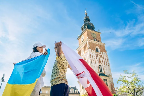 woman and little boy covered with ukraine and poland flag in Krakow city center friendship shelter