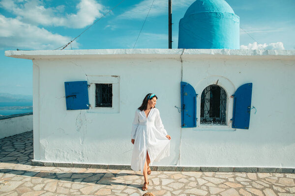 beautiful woman in white dress near old greece church white with blue