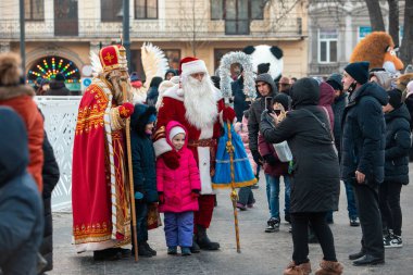 Lviv, Ukraine - December 26, 2021: children taking picture with santa and saint mikolay at christmas holidays outdoors