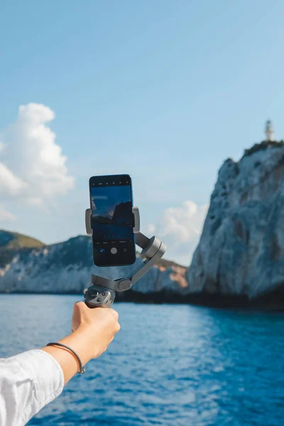 hand holding phone with stabilizator shooting landscape view of lefkada island Greece