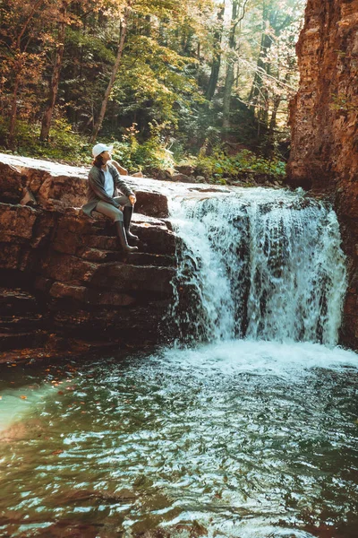 hiker woman enjoying waterfall in autumn forest copy space