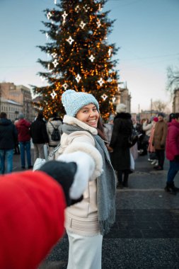follow me concept woman pulling man to christmas tree standing in Lviv city center
