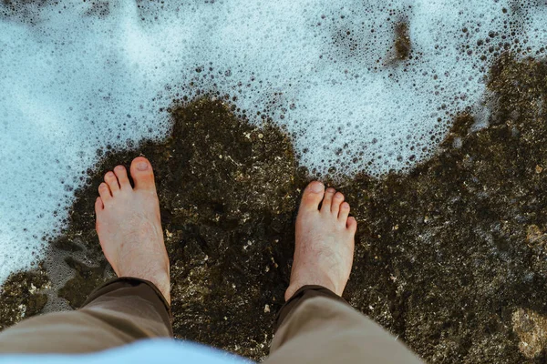 overhead view man barefoot walking by sea rocky beach. copy space