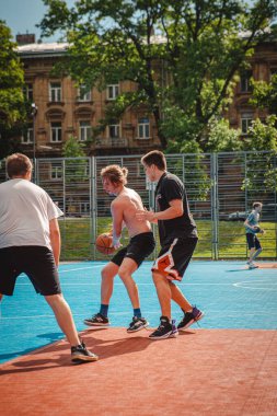 Lviv, Ukrayna - 28 Mayıs 2022: Erkekler açık havada güneşli bir yaz günü basketbol oynuyorlar
