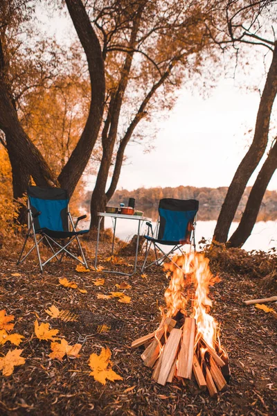 camping autumn place with bonfire and portable chairs no people.