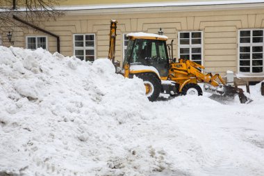 Traktör, kar fırtınasından sonra şehir sokaklarını temizliyor.