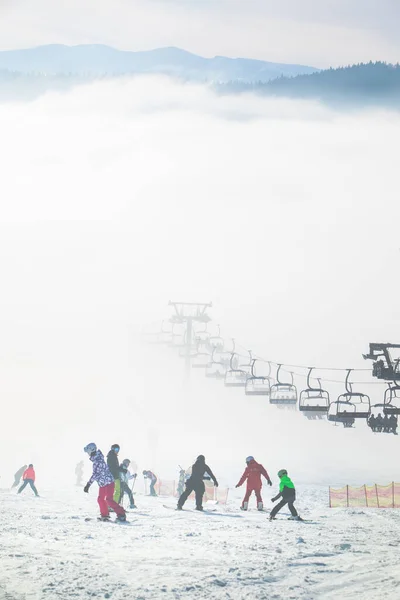 people on the ski slope learning to ride families winter resort misty weather