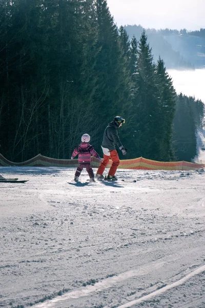 スキー場で娘のスキーヤーを教える若い家族は — ストック写真