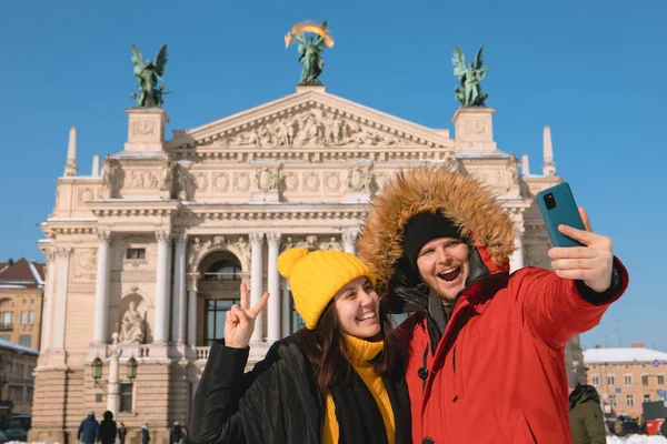 Lviv City Ukrayna 'nın opera binasının önünde selfie çeken iki turist.