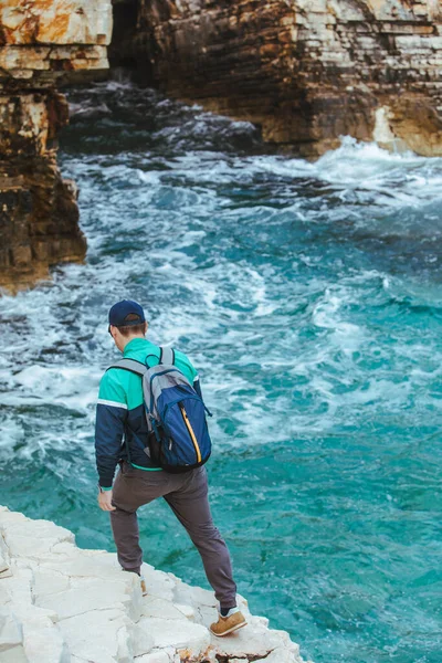Adam tırmanıyor. Kayalık kenar. Deniz manzarasının tadını çıkarıyor. seyahat kavramı