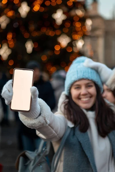 Улыбающаяся Счастливая Женщина Рождественской Городской Ярмарке Держит Телефон Белым Экраном — стоковое фото