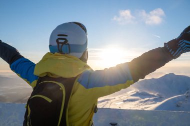 Slovakya dağlarının tepesinde gün batımına bakan kadın kayakçı kış aktiviteleri