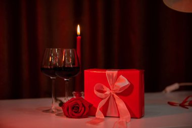 Romantik randevu konsepti. Gözlüklü kırmızı şarap ve mum hediye kutusu.