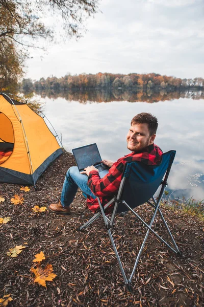 秋の湖の近くの椅子に座ってノートパソコンのフリーランスキャンプのコンセプトで — ストック写真