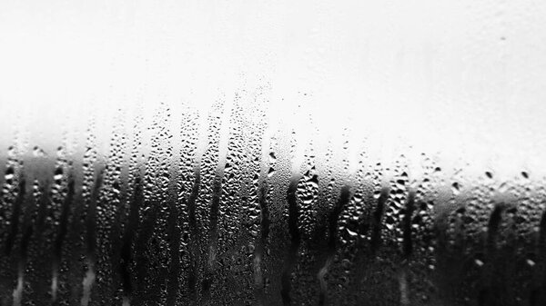 Background of condensation of water droplets on glass, humidity and fog behind glass, bad weather, rain