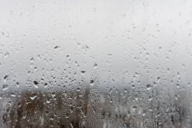 Cam penceredeki buharlaşma, su damlaları, yağmur. Yüksek neme sahip pencere camları. Doğal su yoğunlaşmasının arkaplanı