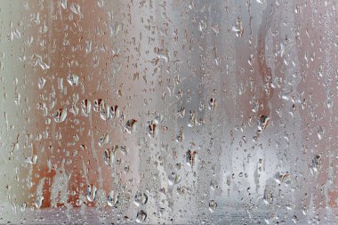 Cam penceredeki buharlaşma, su damlaları, yağmur. Yüksek neme sahip pencere camları. Doğal su yoğunlaşmasının arkaplanı