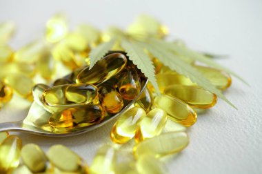 CBD yağ hapları. Beyaz zemin üzerinde şeffaf CBD Cannabidiol kapsülü ve kenevir yaprakları grubu. Organik beslenme takviyeleri kavramı