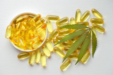 Tıbbi esrar ürünleri, yaprak, kapsüller beyaz arka planda CBD yağı. Biyolojik bitkisel bitkilerle birlikte jelatin softgeller. Organik beslenme takviyeleri kavramı